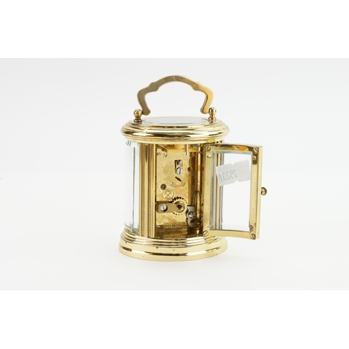 405 - A Modern Oval Brass Cased Carriage Clock with an enamelled face, Black Chaptering & Carrying Handle.... 