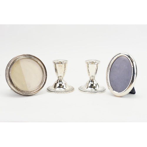 92 - A pair of weighted silver Duchin Creation candle stick holders, along with two silver photo frames.