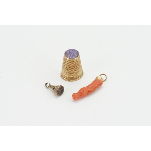 193 - . A 9ct Gold and purple stone mounted thimble, along with a gold coloured seal, carved coral horse.