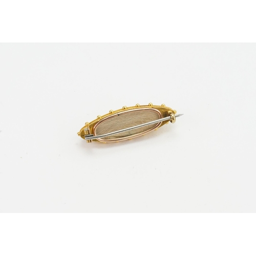 230 - A 18ct gold onyx set mourning brooch, with pearl star decoration. Measures 4cm x 1.3cm. Weight 6.9g.