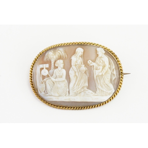 240 - A 9ct gold cameo brooch, depicting three people at a well. Measures 5.4cm x 3.9cm. Weight 16.9g.