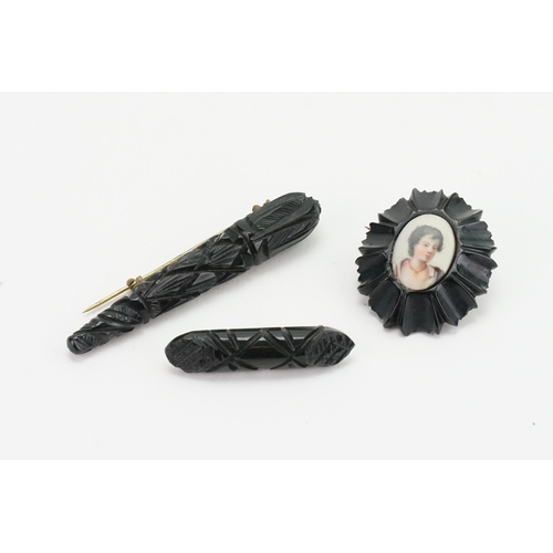 205 - Three carved Jet brooches, one including a painted miniature. Possibly Whitby. Weight  17g.