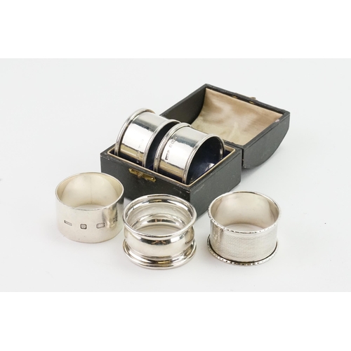 80 - A pair of silver napkin rings cased, along with three others. Weight 117g.