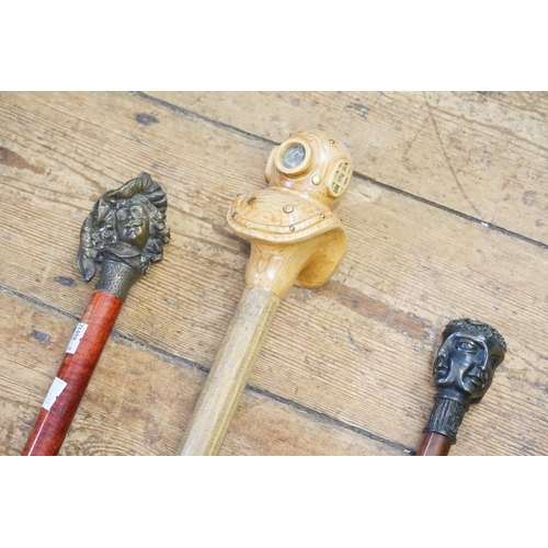 286 - A Carved Pine Diver's Helmet Walking Stick, a Janus Head Walking Stick & a Cast Bronze Cavalier.