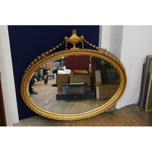 475 - A Regency designed Oval Wall Mirror with Floral Festoons & a Vase Mount. Measuring: 102cms across x ... 