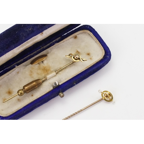 115 - Two cased 15ct gold stick pins, with a button.