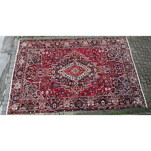 482 - A Rust Blue & Red Ground Floral Medallioned Border Edged Gul & Trefoil Persian Carpet. Measuring: (B... 