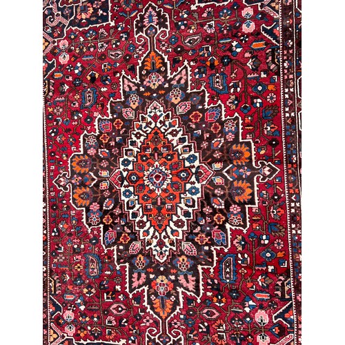 482 - A Rust Blue & Red Ground Floral Medallioned Border Edged Gul & Trefoil Persian Carpet. Measuring: (B... 