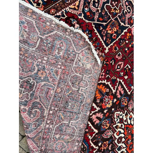 482 - A Rust Blue & Red Ground Floral Medallioned Border Edged Gul & Trefoil Persian Carpet. Measuring: (B... 