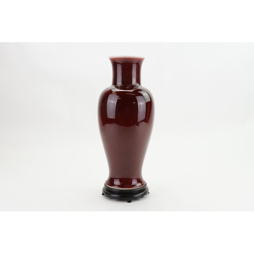 849 - A Red glazed Korean Baluster Vase with a Flared Out Neck. Measuring: 36cms High on a Wooden Stand.