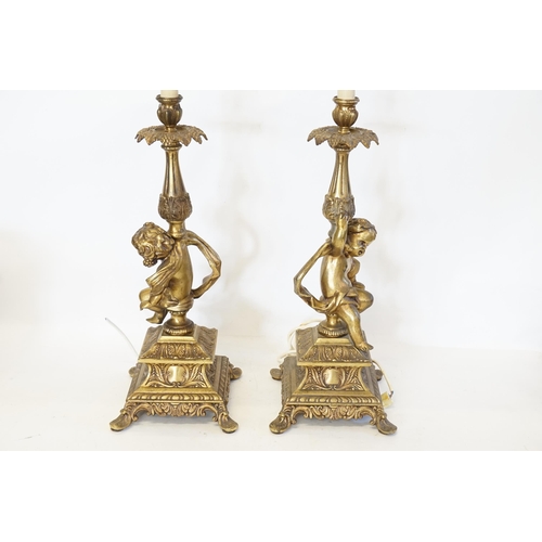 692 - A Pair of Cupid Table Lamps with Rococo decoration standing on square bases. Measuring: 60cms high.