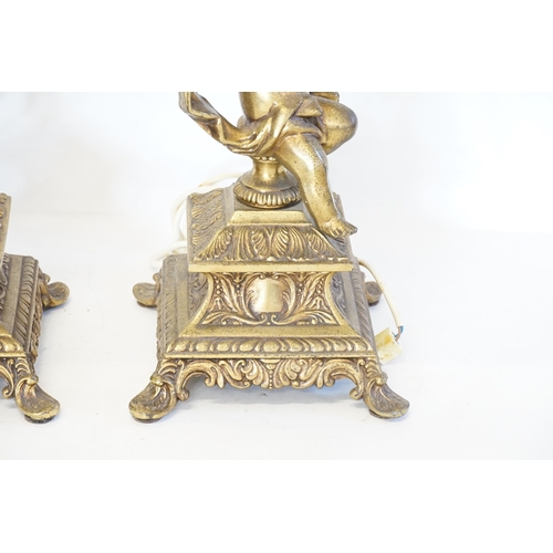 692 - A Pair of Cupid Table Lamps with Rococo decoration standing on square bases. Measuring: 60cms high.