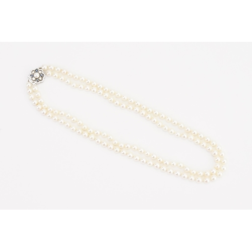 116 - A JKA Köhle marked double string of pearls, with a 14ct white gold diamond & sapphire clasp. Length ... 