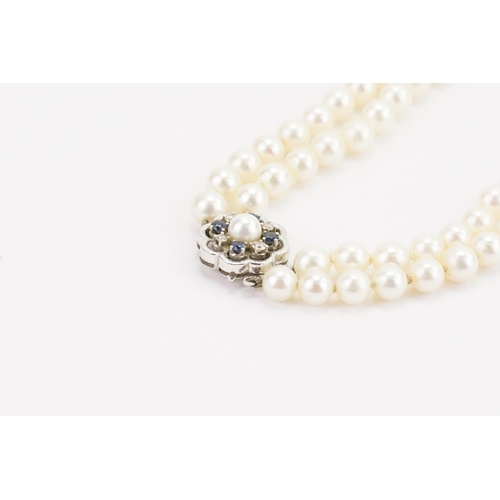 116 - A JKA Köhle marked double string of pearls, with a 14ct white gold diamond & sapphire clasp. Length ... 