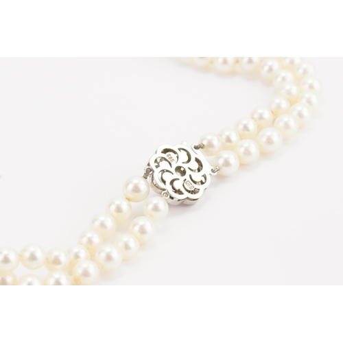 116 - A JKA Köhle marked double string of pearls, with a 14ct white gold diamond & sapphire clasp. Length ... 