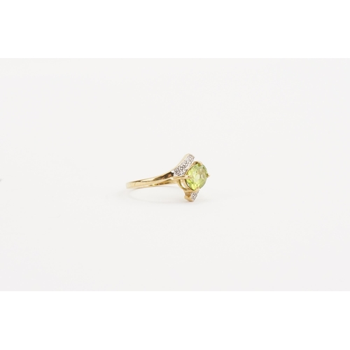 63 - A 9ct gold green stone and diamond set ring, in the cross over design. Weight 2.3g. Size N.