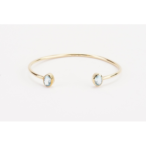 88 - A 9ct gold aquamarine mounted bangle, set with two aquamarines at approximately 7.4mm x 5.1mm. Weigh... 