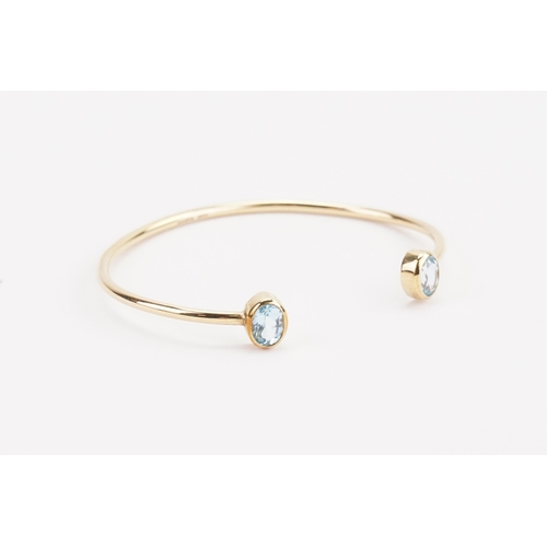 88 - A 9ct gold aquamarine mounted bangle, set with two aquamarines at approximately 7.4mm x 5.1mm. Weigh... 