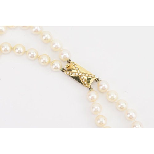 85 - A double strand of Garrard pearls, set with a 18ct yellow gold and diamond set clasp. Set with 59 an... 