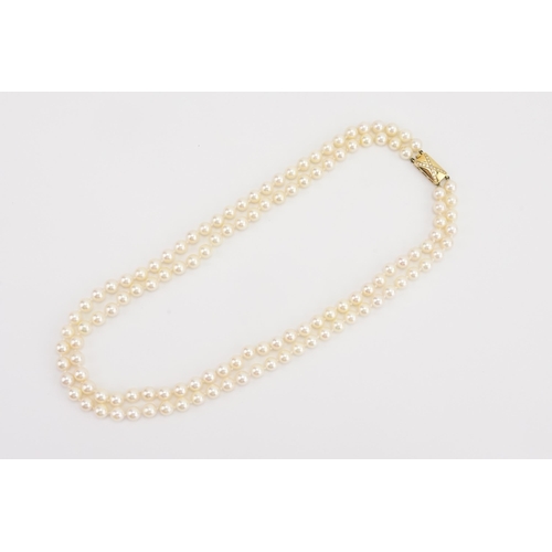 85 - A double strand of Garrard pearls, set with a 18ct yellow gold and diamond set clasp. Set with 59 an... 