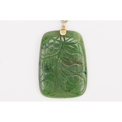 142 - A 9ct gold mounted nephrite brooch. With carved design. Weight 24.1g. Size 48.5mm x 35mm.