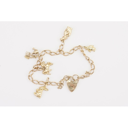 89 - A 9ct gold charm bracelet, hung with various charms to include a rabbit, gardening tools etc. Weight... 