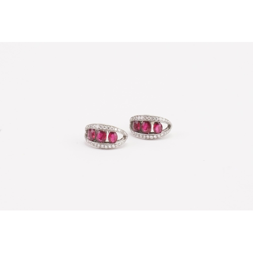 110 - A pair of 18ct gold diamond and ruby set pierced earrings. Surrounded by diamonds. Largest ruby appr... 