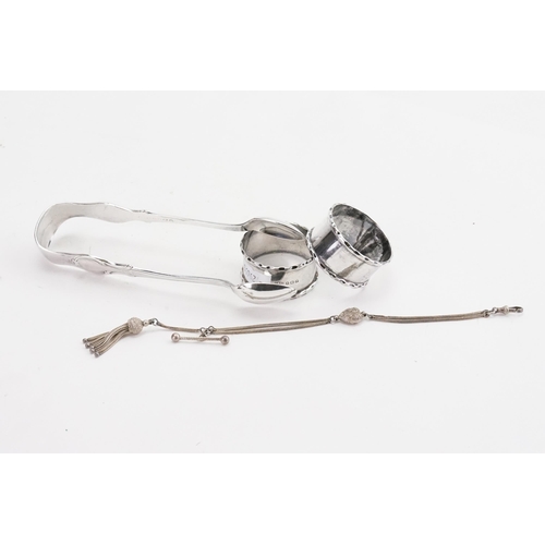 15 - A pair of silver napkin rings along with silver plated tongs and a silver chain.