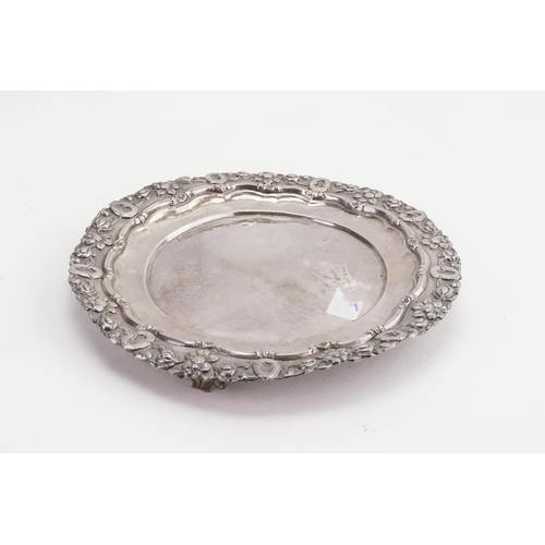 39 - A late 19th Century silver coloured white metal tray, decorated with flowers, resting on stamped fee... 
