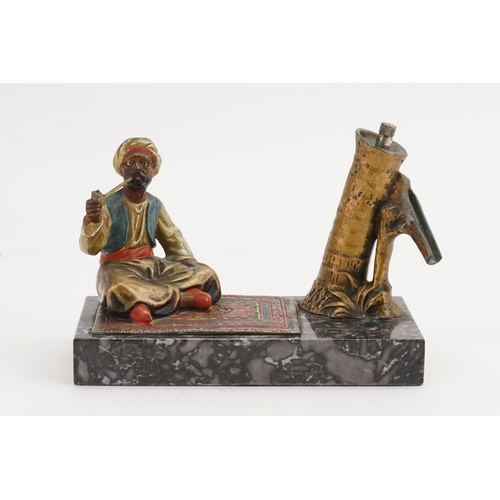 657 - An Austrian painted Table Lighter designed as an Arab on a Carpet on a Marble base.