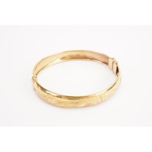 107 - A 9ct gold engraved bangle. Weight 10.6g.