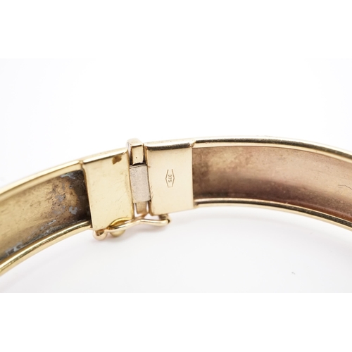 107 - A 9ct gold engraved bangle. Weight 10.6g.