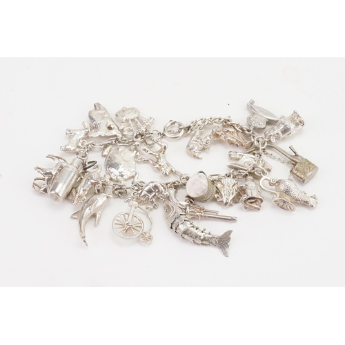 175 - A Vintage Silver Charm Bracelet to include around 20 charms. Weighing: 77.2 grams.