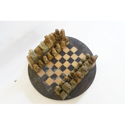 698 - An African Carved Chess Set with Native Figures & a Chess Board to match.