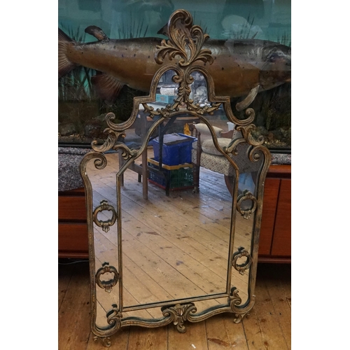 541 - A metal framed mirror, in floral scroll decoration. Measuring 127cm high x 80cm wide.