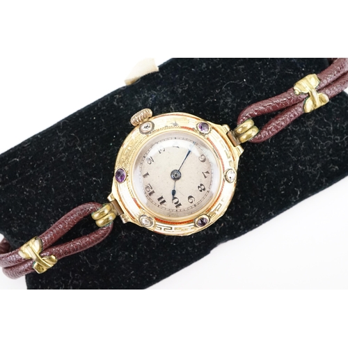 180 - A 18ct gold diamond and amethyst set wrist watch, Greek key white and red enamel design, brown leath... 