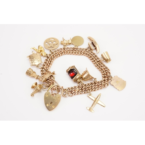 119 - A circa 1960s 9ct gold double curb charm bracelet, with various gold charms to include spitfire, gob... 