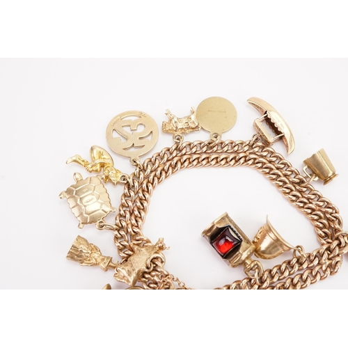 119 - A circa 1960s 9ct gold double curb charm bracelet, with various gold charms to include spitfire, gob... 