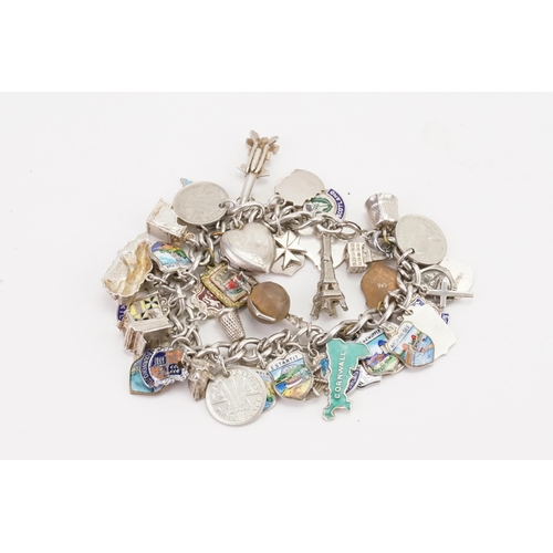 173 - A large silver curb link charm bracelet, to include various charms such as enamelled locations etc. ... 