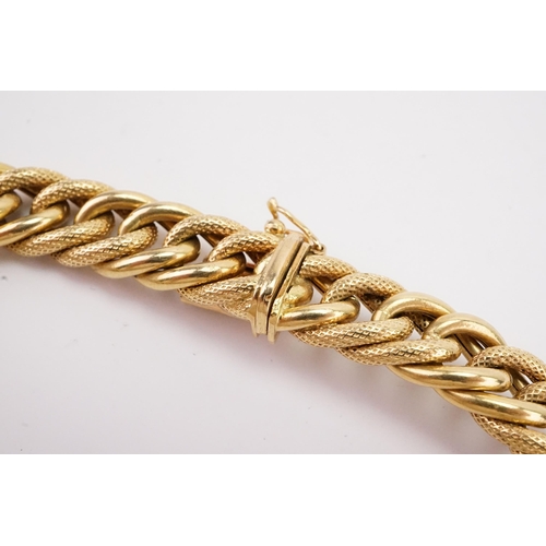 97 - A 18ct gold heavy curb link bracelet, with engraved design. Weight 21.8g. Length 20cm.