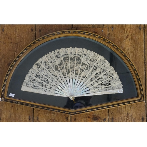 712 - A Victorian Mother of Pearl Fan contained in a Glass Fronted Fan Shaped Frame.