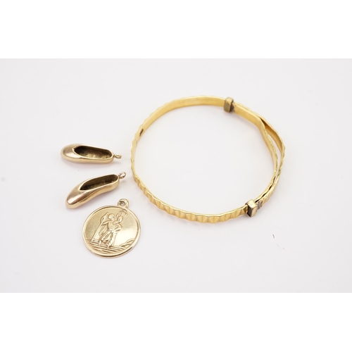 97 - A 9ct gold St Christopher, along with a 9ct gold pair of Ballet shoes, and a rolled gold bangle. Wei... 