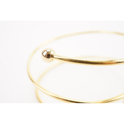 114 - Ex Collection of Mariam Jans Daughter. A high carat gold spiral arm bangle. Weight 26.8g. (No. 15) D... 