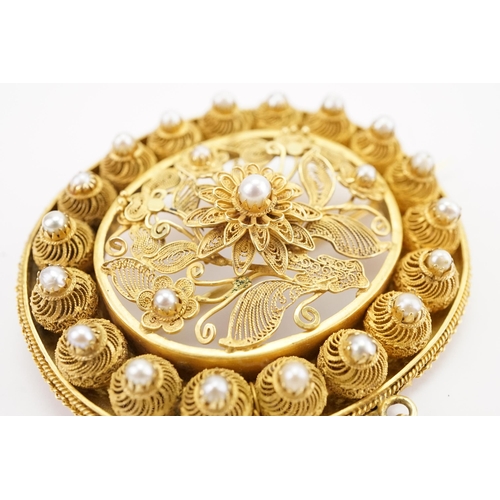 94 - A Iranian high carat gold and pearl set filigree brooch, along with the matching pearl set earrings.... 