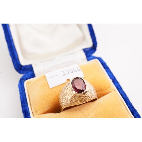 155 - A garnet set signet ring, the garnet is set in a unmarked raised setting. Size V. Approximate size o... 