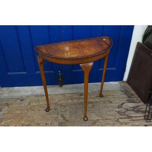 580 - A Walnut Veneered Demi-Lume Side Table resting on three pad feet. Measuring: 74cms across x 37cms de... 