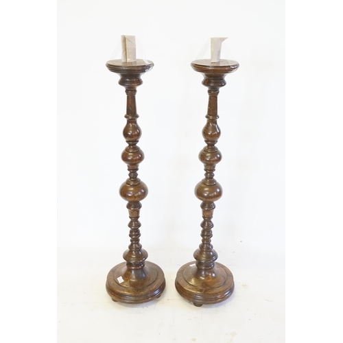 361 - A Pair of Turned Oak Candlestick holders resting on bun feet. Measuring 60cms high.