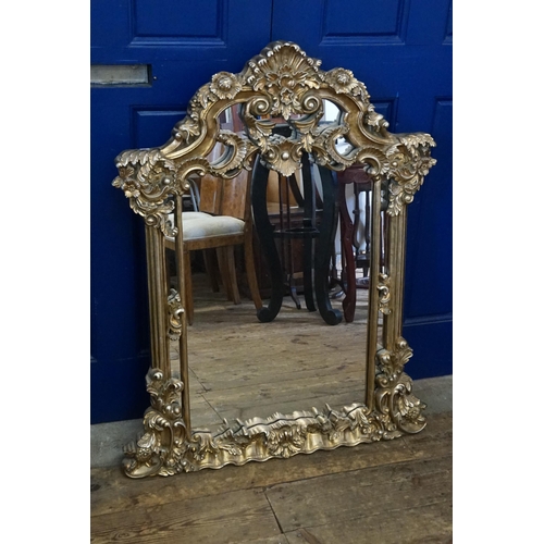 557 - A Reproduction Rococo Heavy Framed Wall Mirror decorated with Flowers. Measuring: 110cms x 84cms.