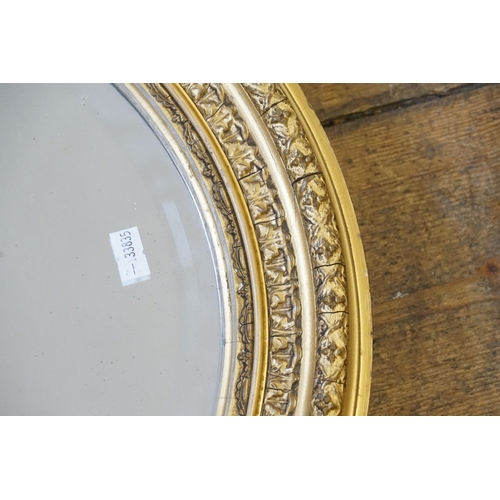 562 - An Oval Gilt Framed Wall Mirror in Gesso. Measuring 55cms x 48cms. Along with one other.