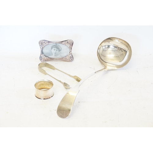 99 - A Silver Plated Soup Ladle, Photo Frame, Sugar Tongs & a Napkin Ring.